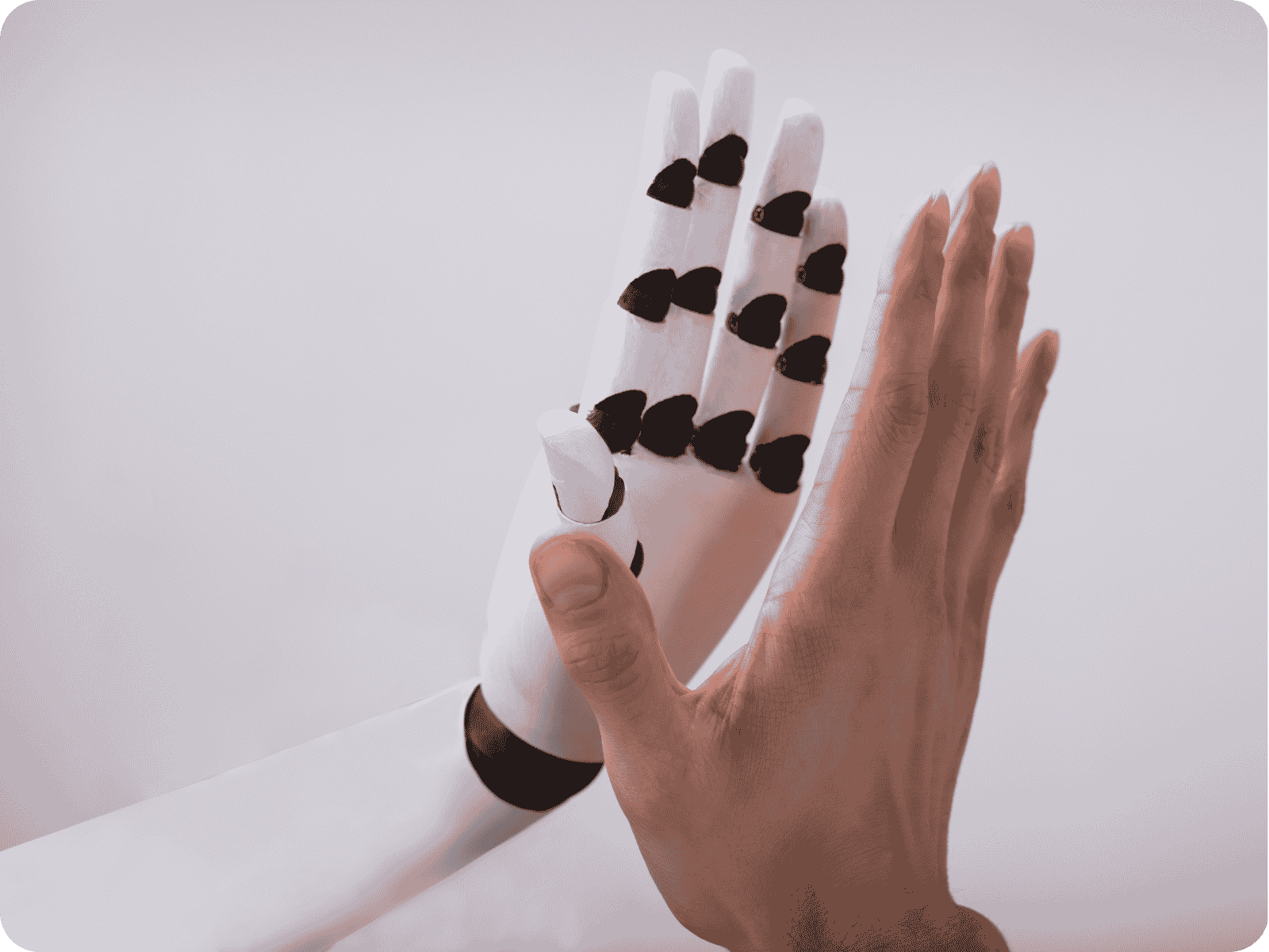 Robotic hand with sensor pads on its fingers giving a high-five to a human hand, representing AI agents working alongside people in field service