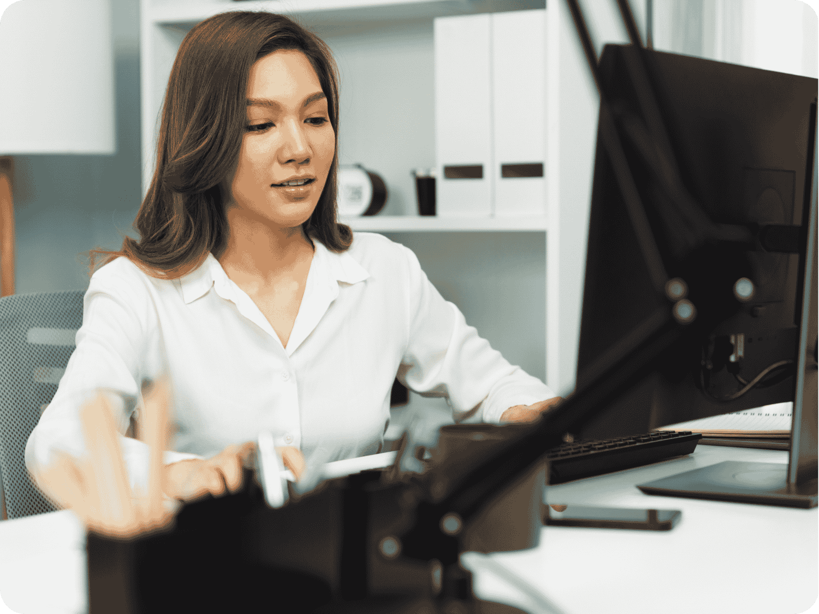 A contractor office manager reviewing job quotes and scheduling on a desktop computer using custom CRM software.